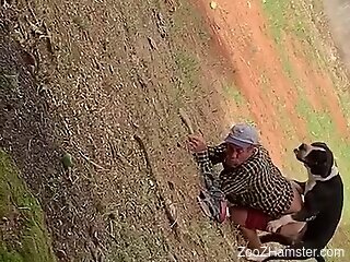 Clothed old man filmed in a field getting laid with a dog
